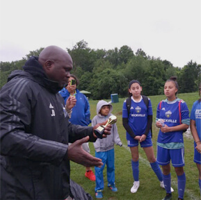 Coach speaking to youth soccer players outdoors