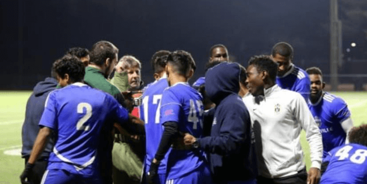 Soccer team huddling on field at night