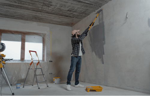 Person painting ceiling with roller in room