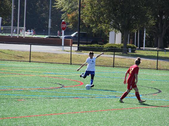 Soccer player kicking ball past defender