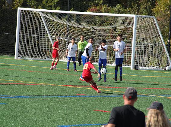 Red soccer player kicking ball toward goal